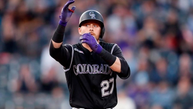 Colorado Rockies shortstop Trevor Story, front, reaches with his